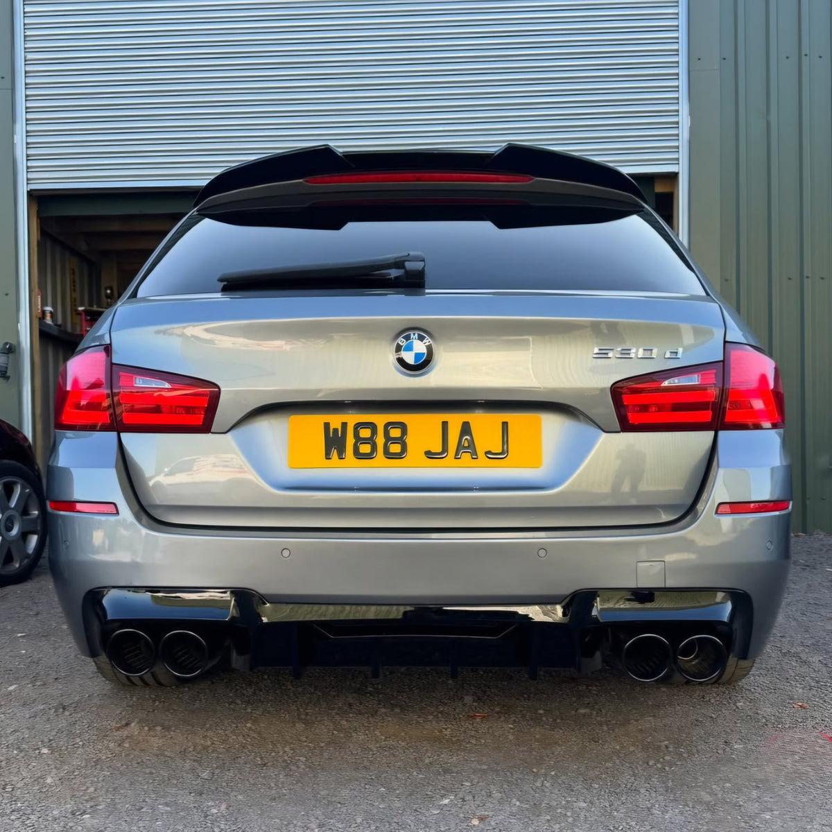 Gloss black competition-style rear diffuser with quad exhaust outlets for BMW F10 5 Series 2010-2017, showcasing a sleek, aerodynamic design.