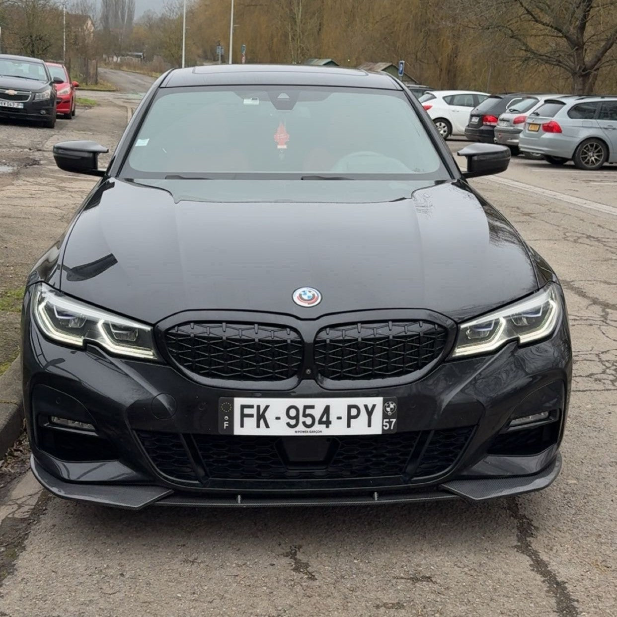 Black BMW car with a visible license plate in a parking lot.