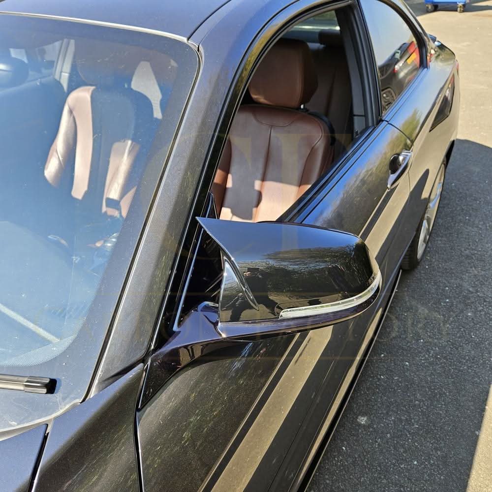 Gloss black M4 style mirror covers for BMW 1, 2, 3, and 4 Series, shown on a vehicle's side mirrors.