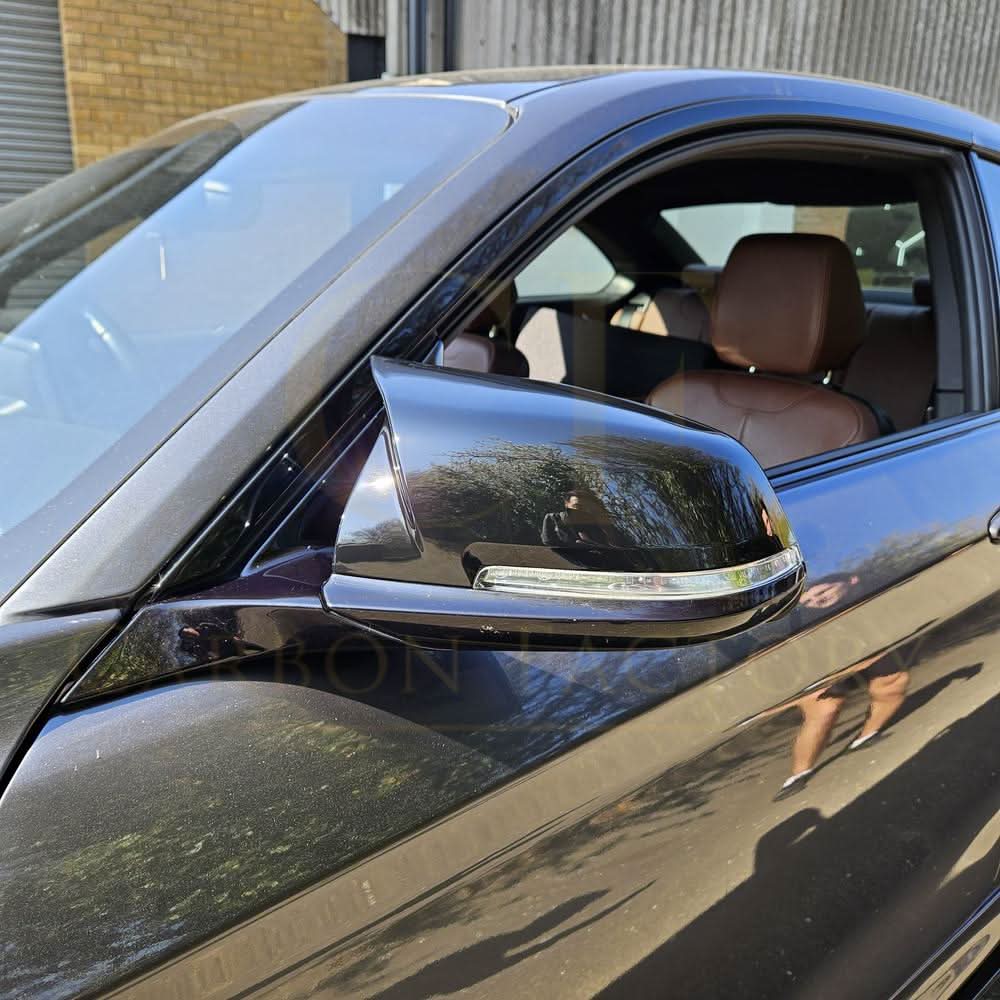 Gloss black M4 style mirror covers for BMW 1, 2, 3, and 4 Series shown on a vehicle, designed as replacement mirror covers.