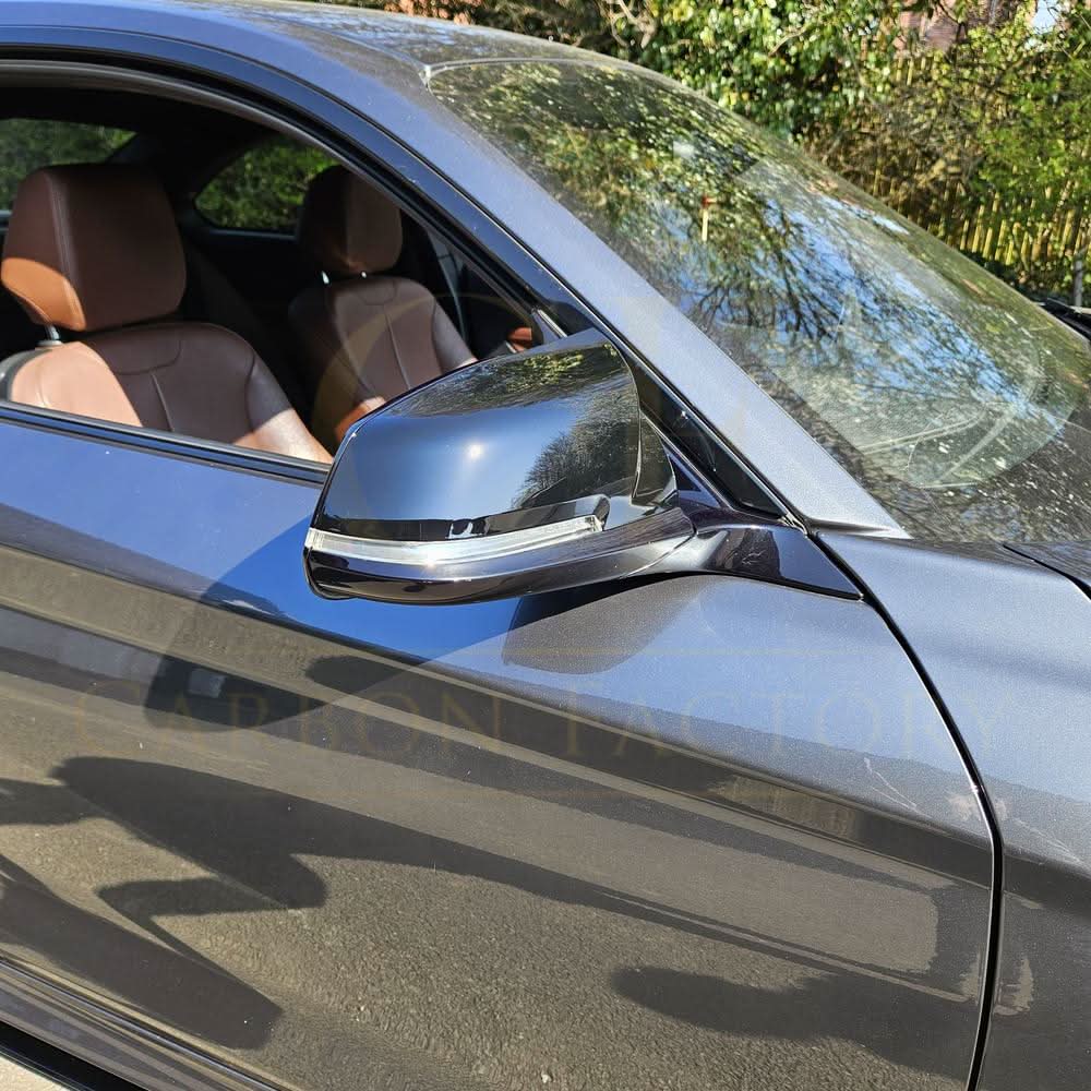 Gloss black M4 style replacement mirror covers for BMW 1, 2, 3, and 4 Series, shown on a vehicle.