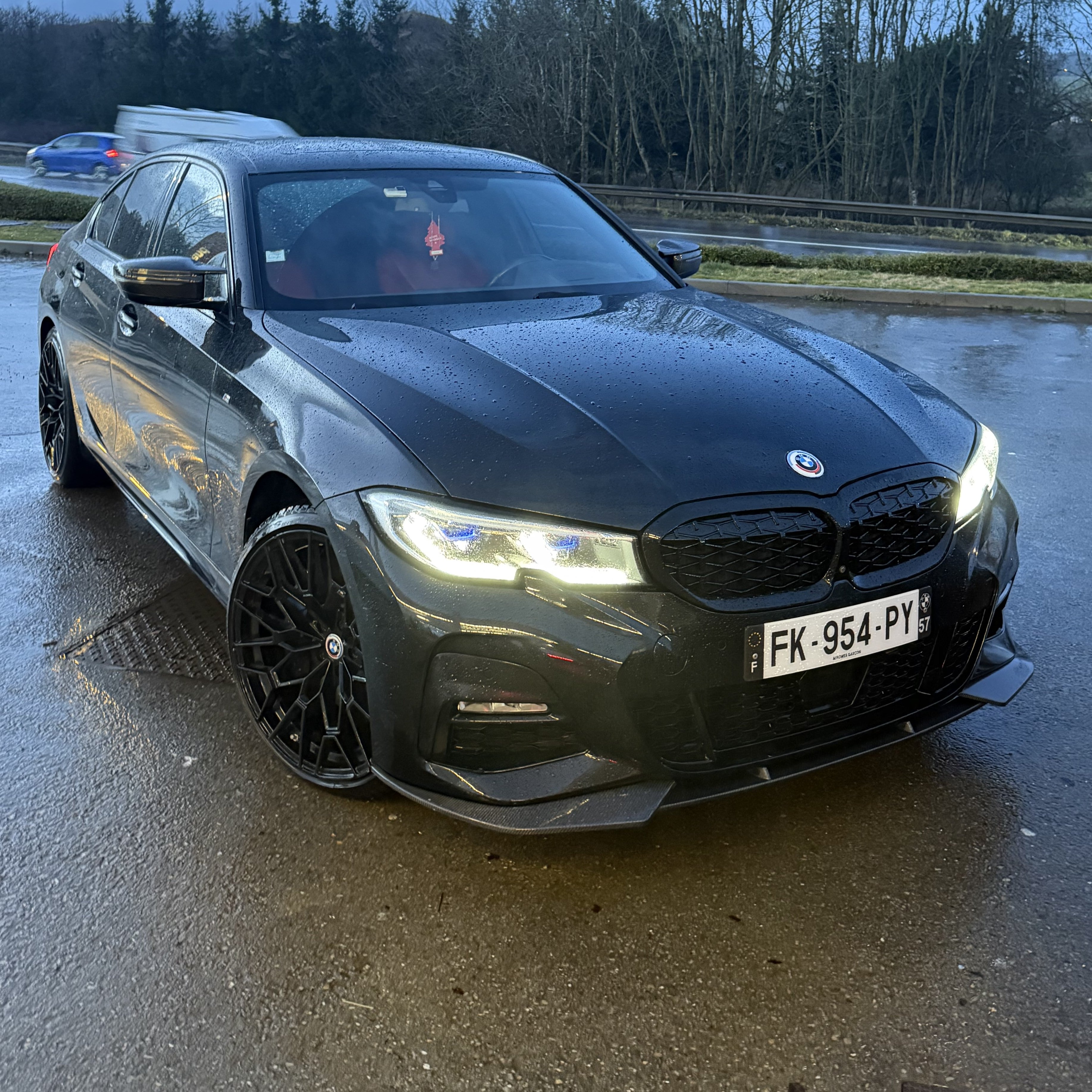Black BMW car on a wet road with trees in the background