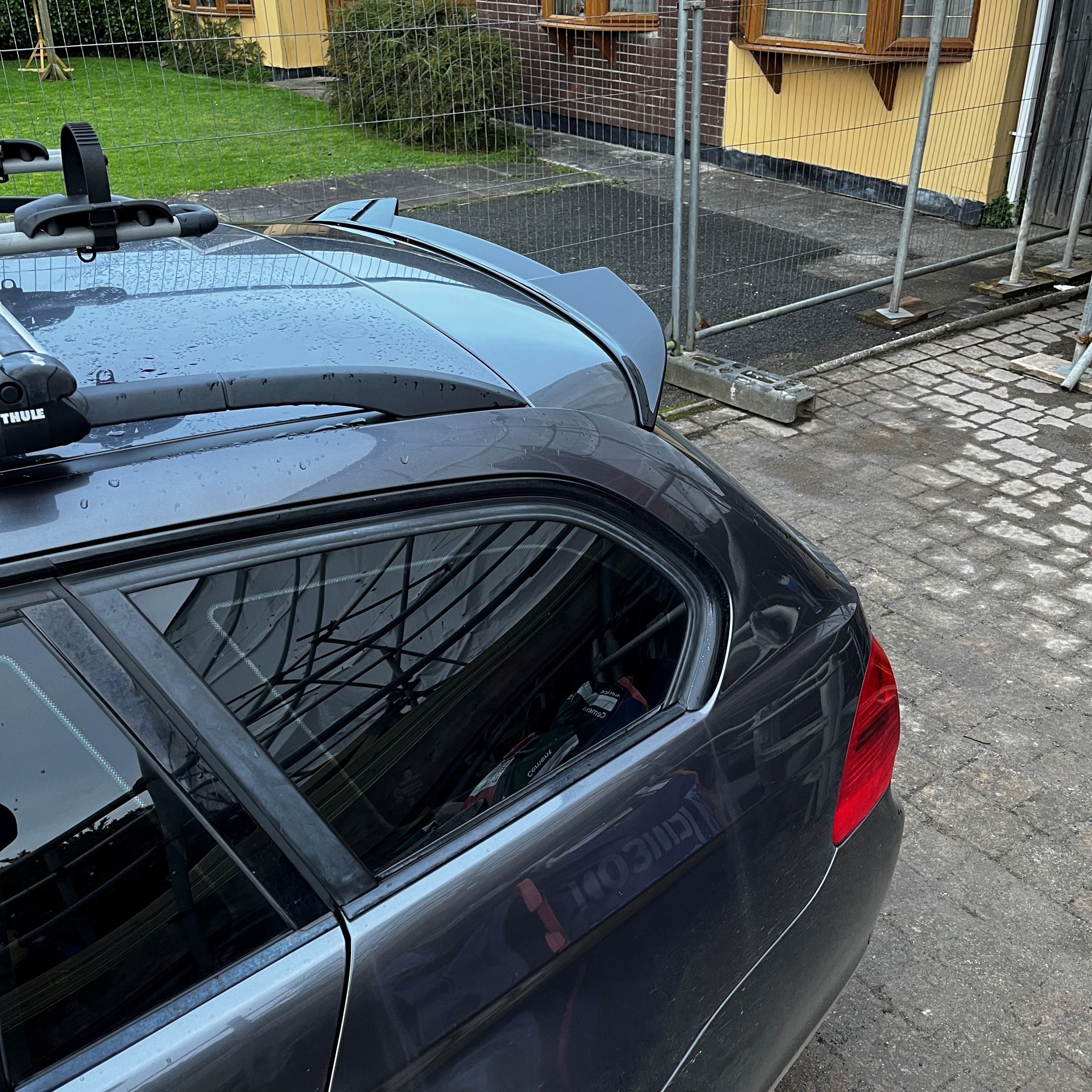 Car with a roof rack parked on a driveway next to a house.