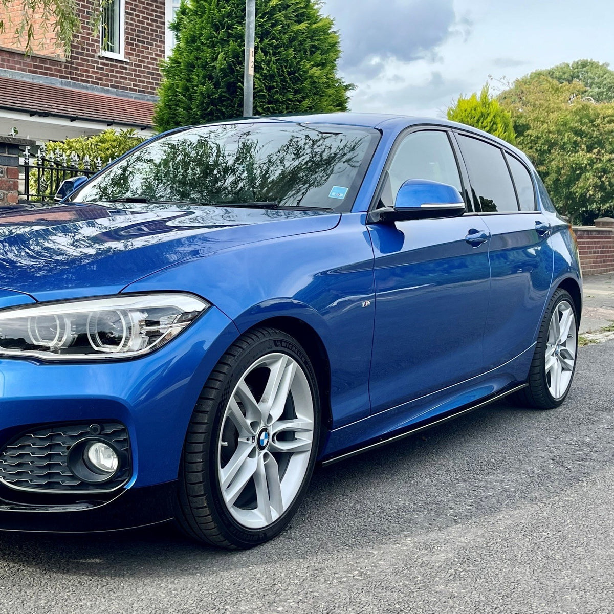 Gloss Black side skirt for BMW F20 1 Series 12-19, showing sleek, aerodynamic design and finish on car side profile.