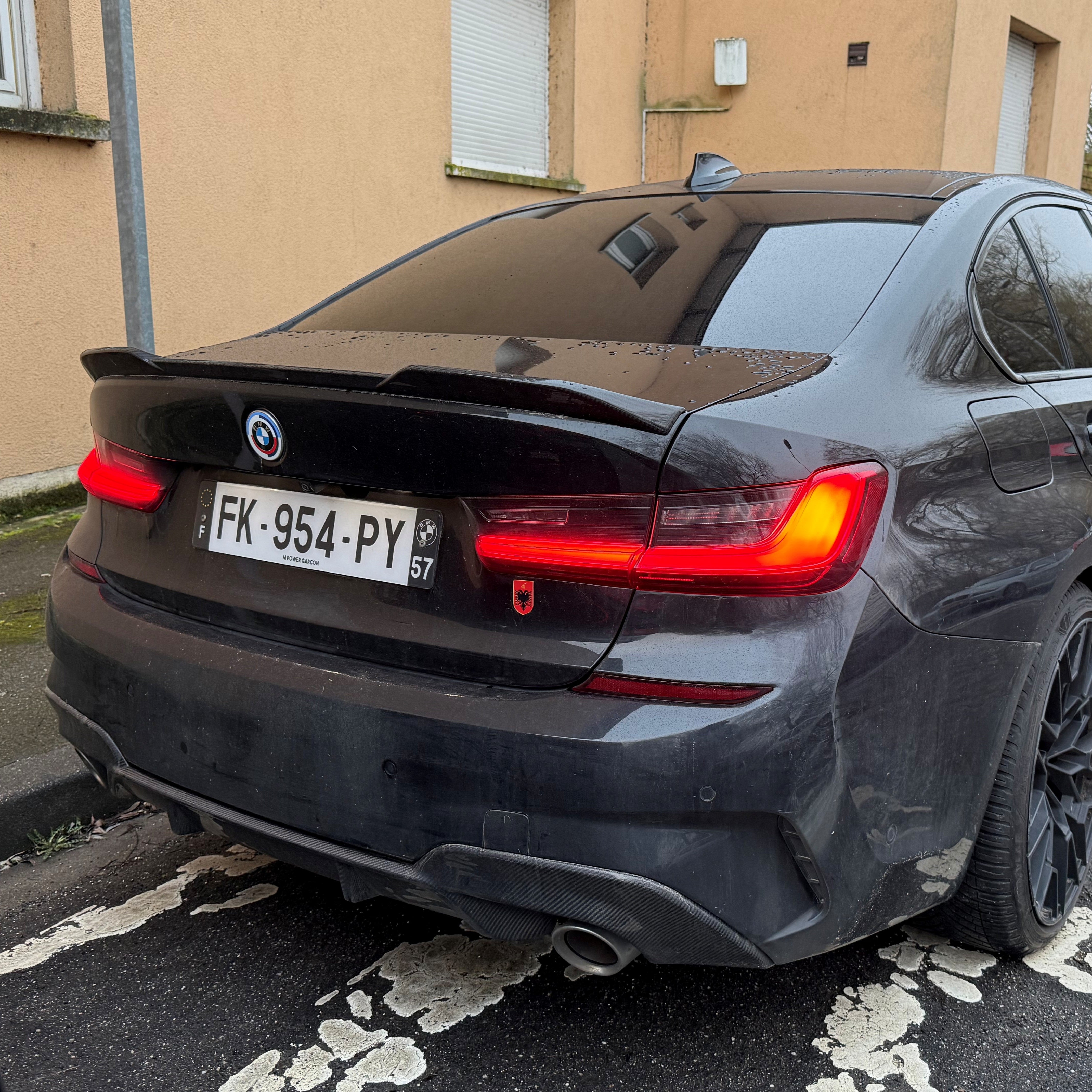Black BMW car parked on a street with a visible license plate.
