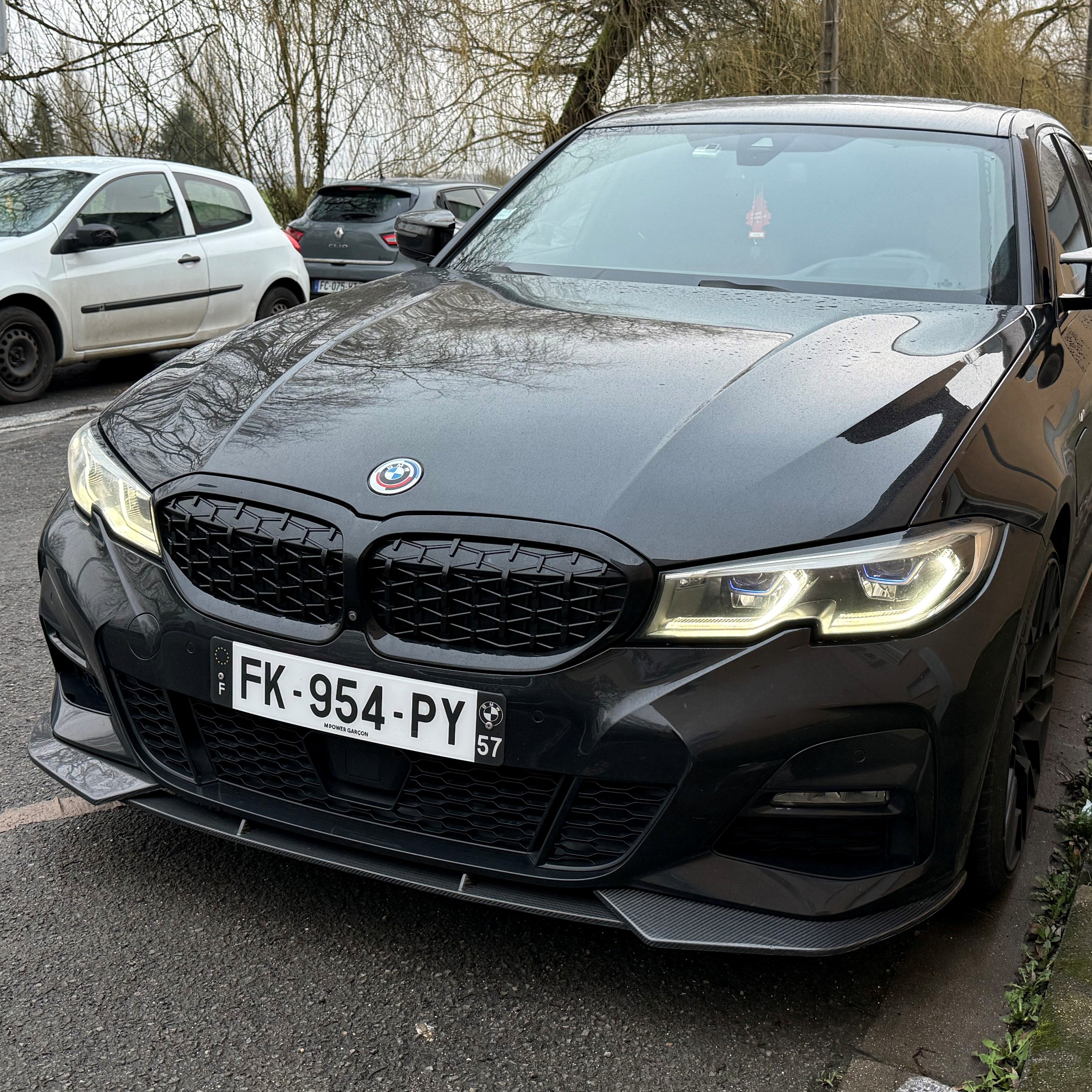 Black BMW car parked on a street with trees and other cars in the background