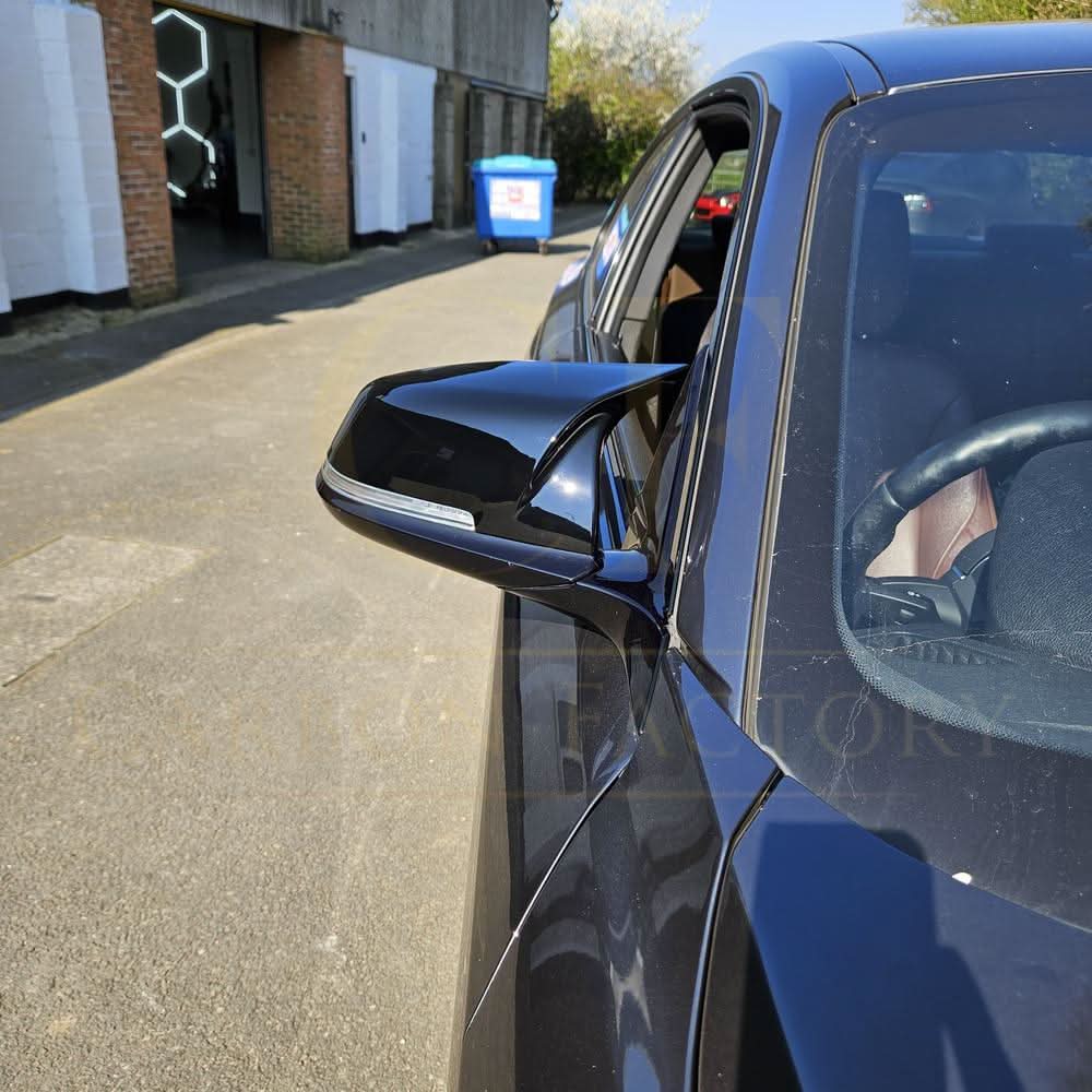 Gloss black M4 style mirror covers for BMW 1, 2, 3, and 4 Series, shown fitted on vehicle with reflective finish.