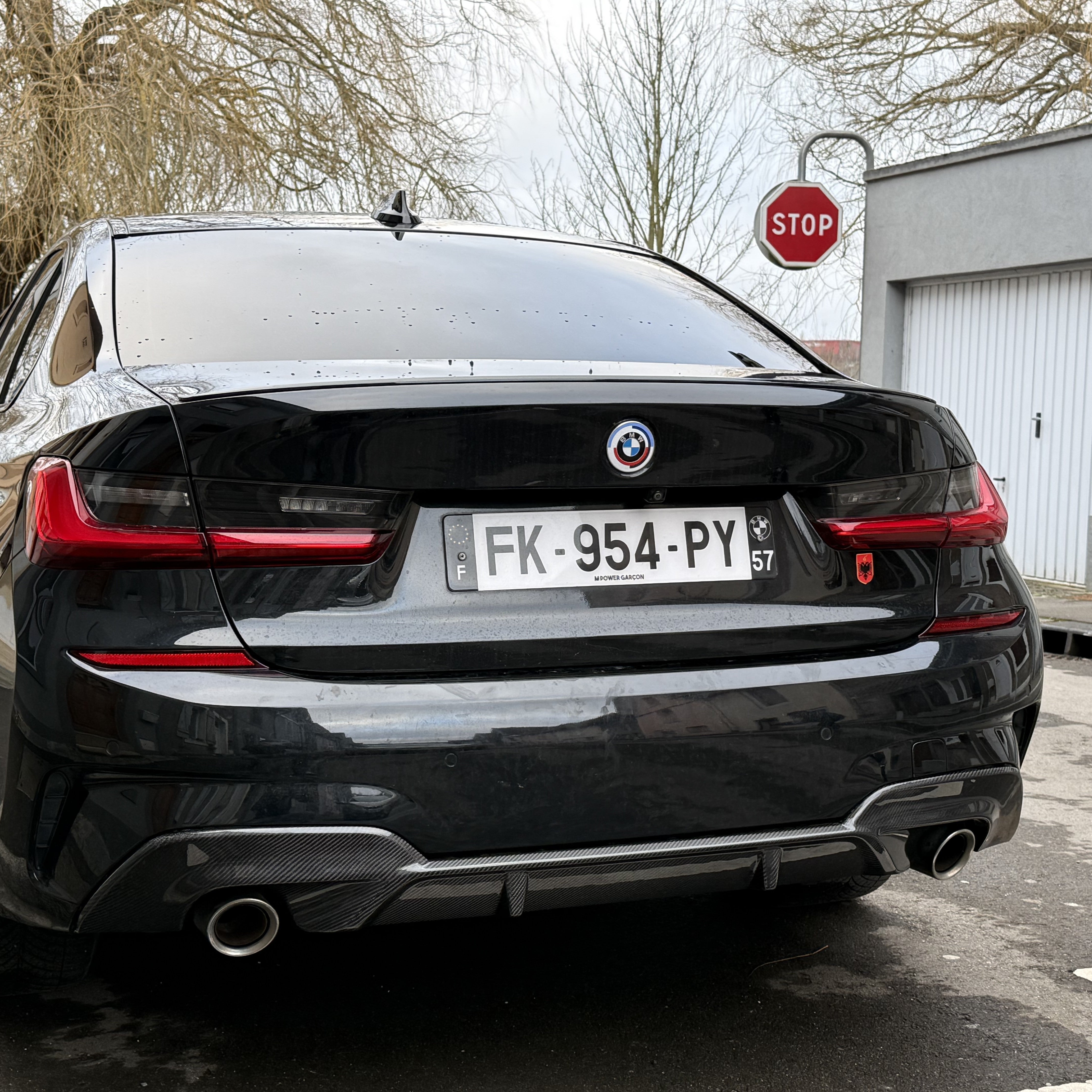 Black BMW car with a visible license plate in an outdoor setting.