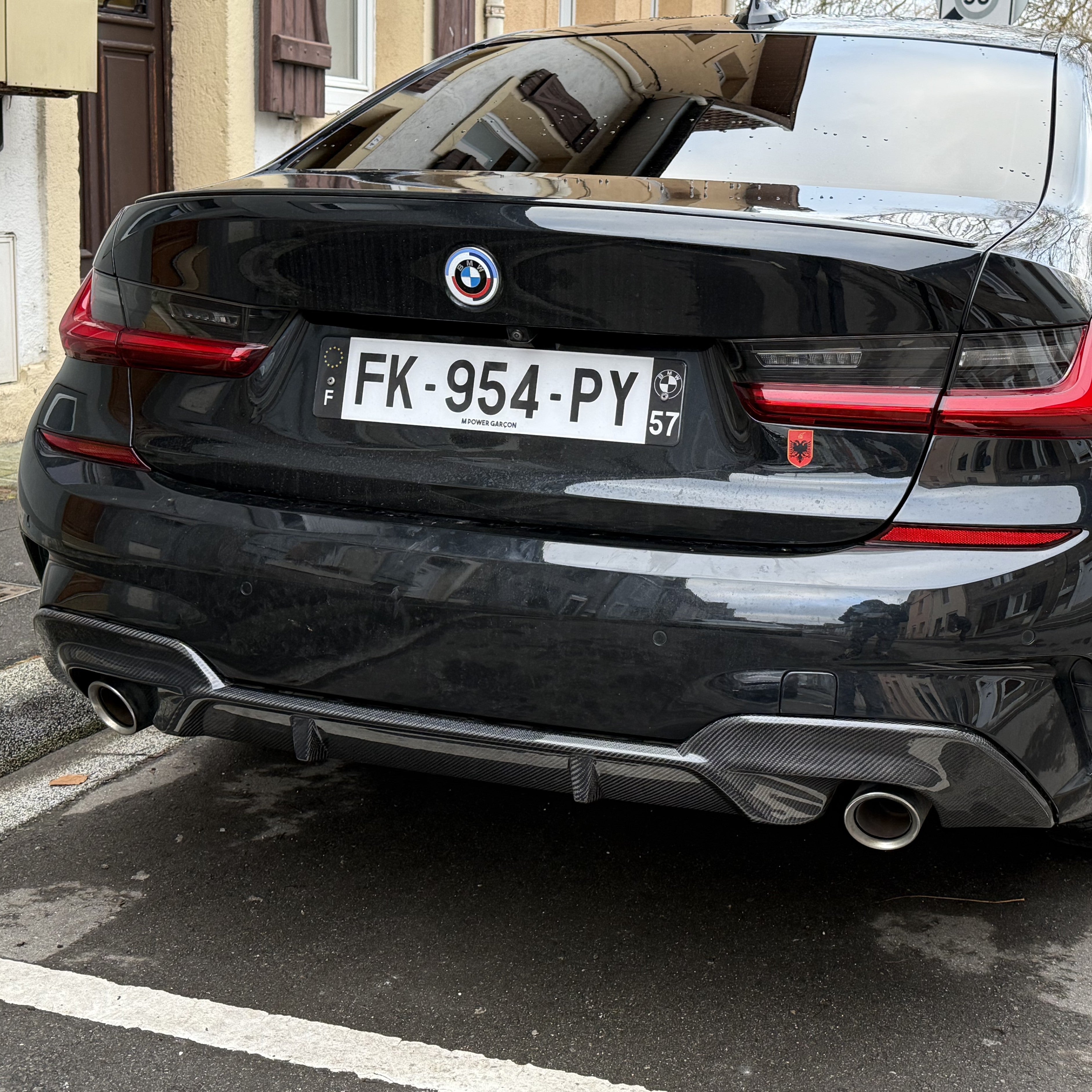 Black BMW car with a visible license plate on a street.