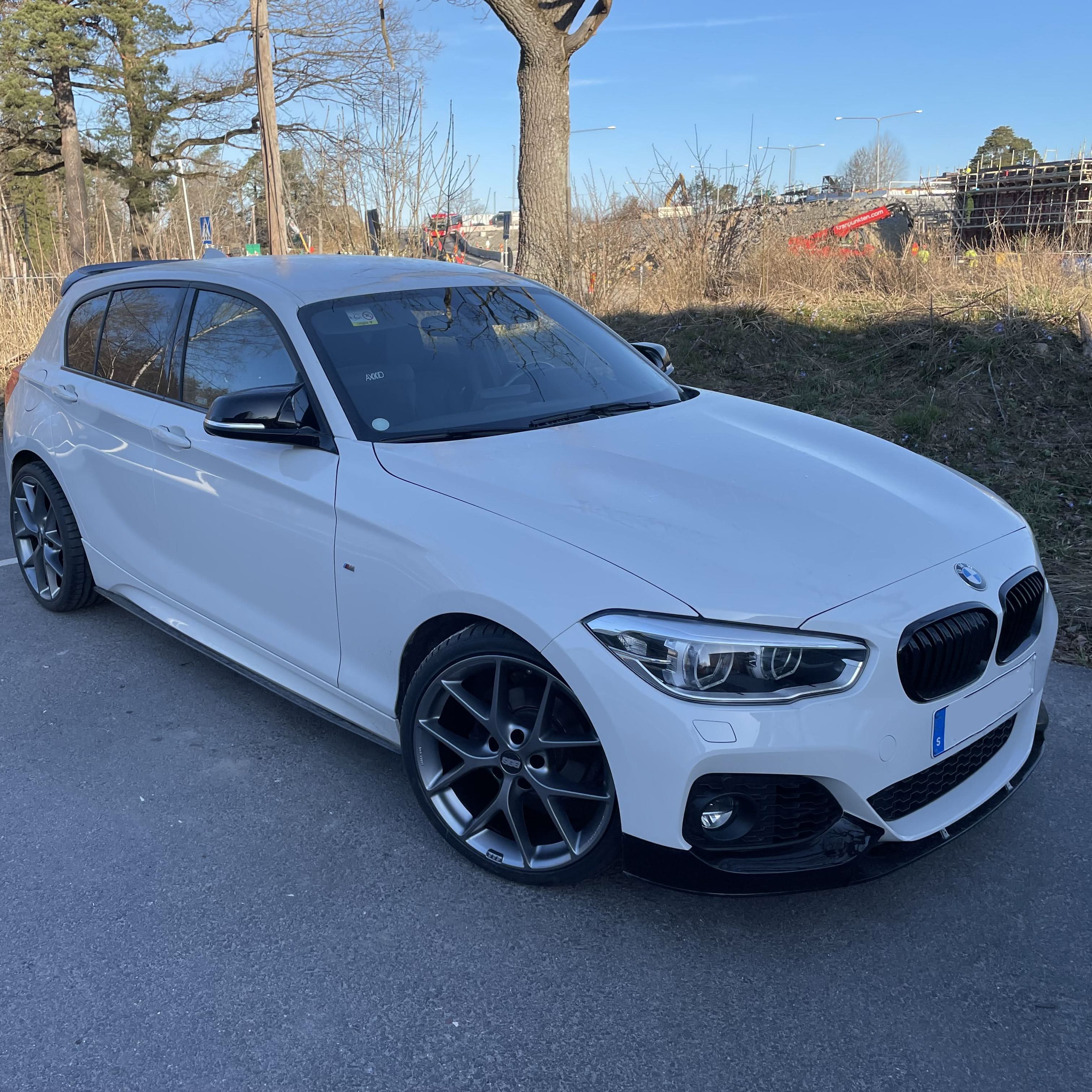 Gloss black front splitter for BMW F20 F21 1 Series LCI 2015-2019, featuring aerodynamic design and high-quality finish.
